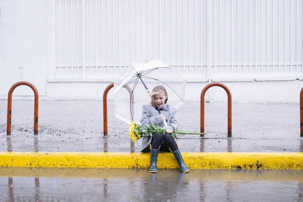 Bambina seduta in strada con un mazzo di fiori in r — Foto Stock