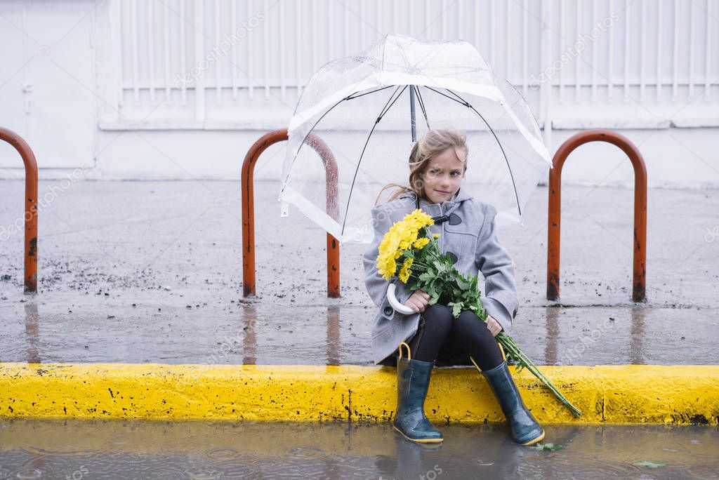 little girl sitting in the street with a bouquet of flowers in r