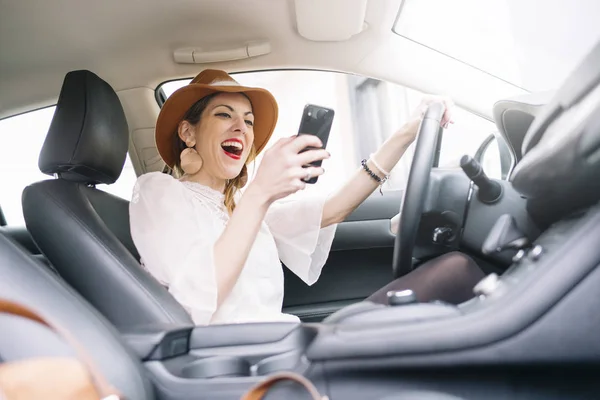 美丽的年轻女子在车里用她的手机 — 图库照片