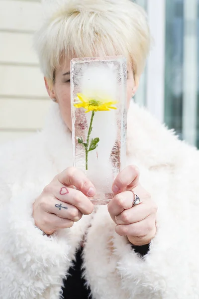 Mulher segurando um bloco de gelo, com flor amarela — Fotografia de Stock