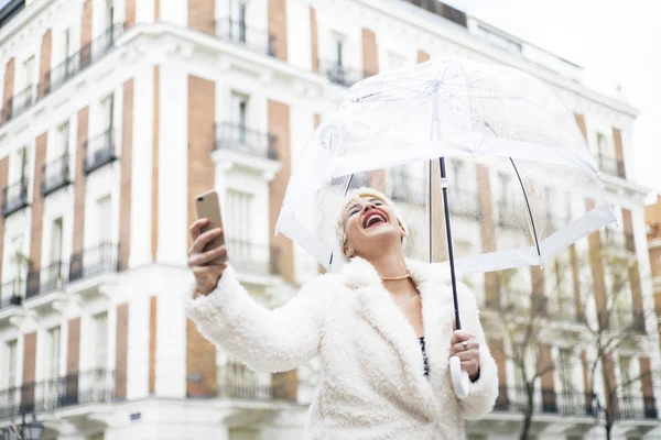 Mulher loira com guarda-chuva mensagens no smartphone — Fotografia de Stock