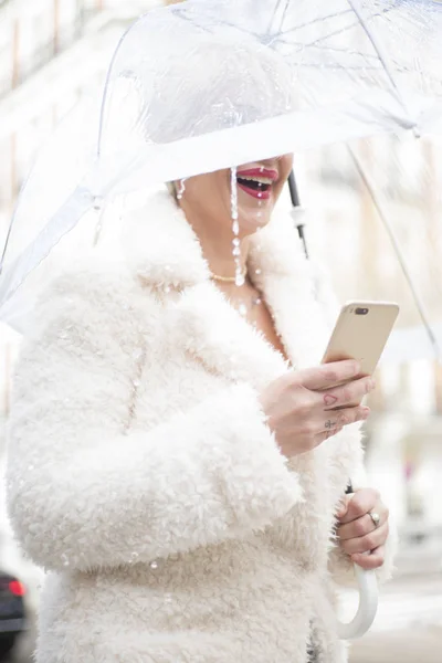 Блондинка с зонтичным текстом на смартфоне — стоковое фото