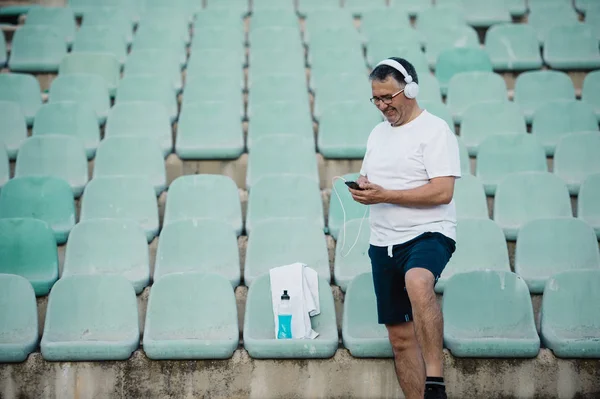 Hombre mayor preparando su música antes de correr — Foto de Stock