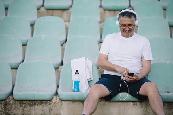 Hombre mayor preparando su música antes de correr — Foto de Stock