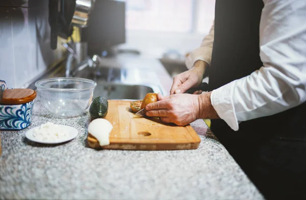 Man of 59 year old cutting vegetables in the kitchen of his hous