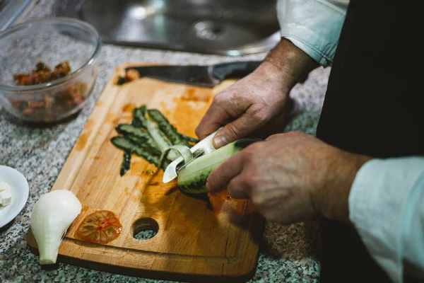 Man of 59 year old cutting vegetables in the kitchen of his hous