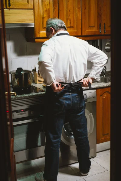 Man van 59 jaar oude werken in de keuken van zijn huis. — Stockfoto