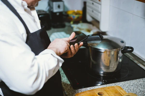 Hombre de 59 años con smartphone en la cocina de su casa . — Foto de Stock