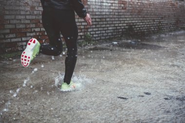 Kadının yağmurlu günde açık havada spor yapması