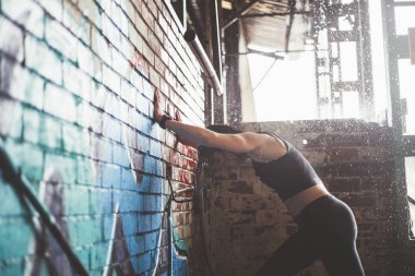 Kadın yağmurlu günde açık havada spor yapıyor. Stretc gerçekleştirir