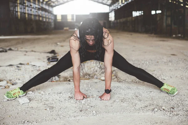 Kadın yağmurlu günde açık havada spor yapıyor. Stretc gerçekleştirir