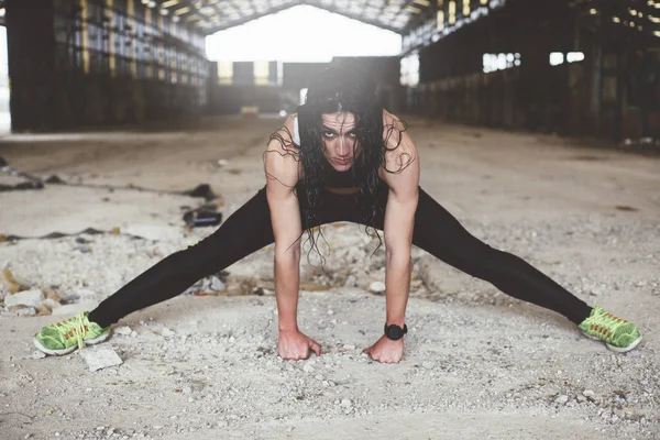 Kadın yağmurlu günde açık havada spor yapıyor. Stretc gerçekleştirir