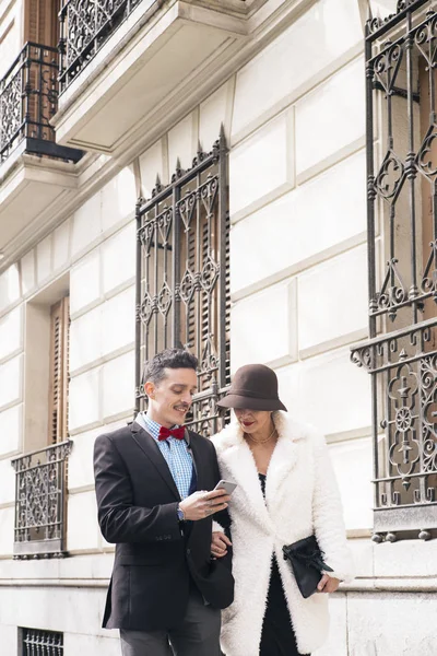 Hombre y mujer con paraguas mensajes de texto en el teléfono inteligente — Foto de Stock