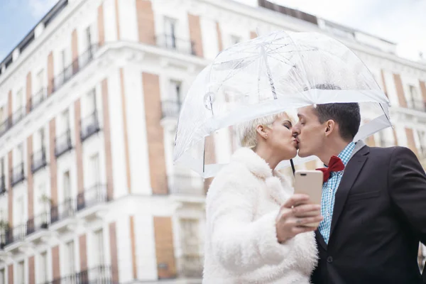 Mann und Frau mit Regenschirm-SMS auf Smartphone — Stockfoto