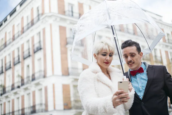 Мужчина и женщина с зонтичным текстом на смартфоне — стоковое фото