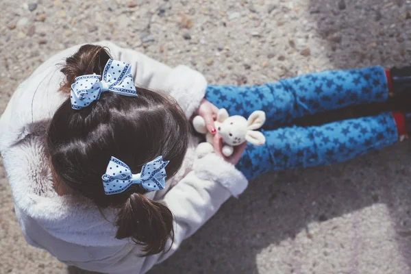 Menina brincando ao ar livre com bicicleta e ursinho de pelúcia — Fotografia de Stock