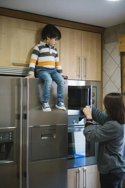 Criança está sentada acima da geladeira — Fotografia de Stock