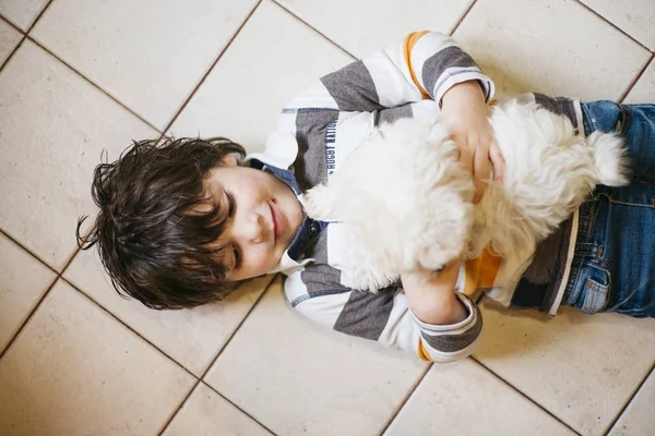 Kleine jongen liggend met witte hond — Stockfoto