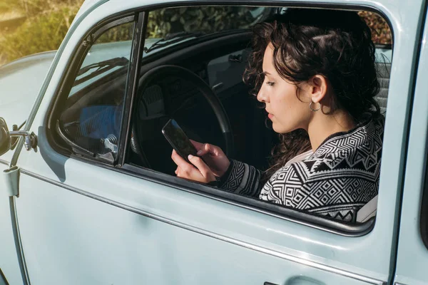 美丽的年轻女子在车里用她的手机. — 图库照片
