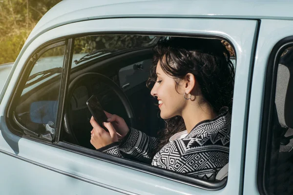 Krásná mladá žena pomocí svého mobilního telefonu v autě. — Stock fotografie