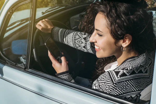 Piękna młoda kobieta za pomocą jej telefon komórkowy w samochodzie. — Zdjęcie stockowe