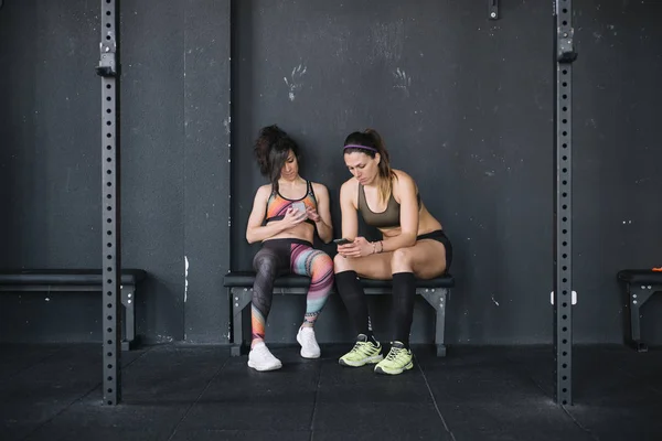 Дві жінки з телефоном у спортзалі — стокове фото