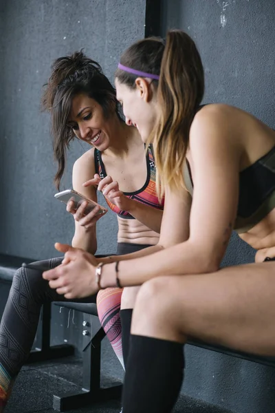 Дві жінки з телефоном у спортзалі — стокове фото