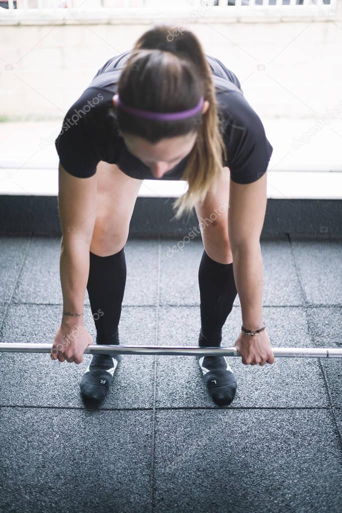 Determined sportswoman lifting heavy barbell