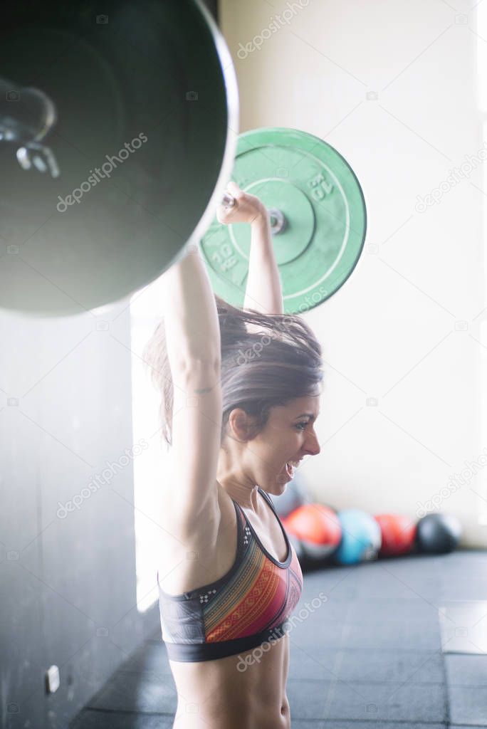 Determined sportswoman lifting heavy barbell