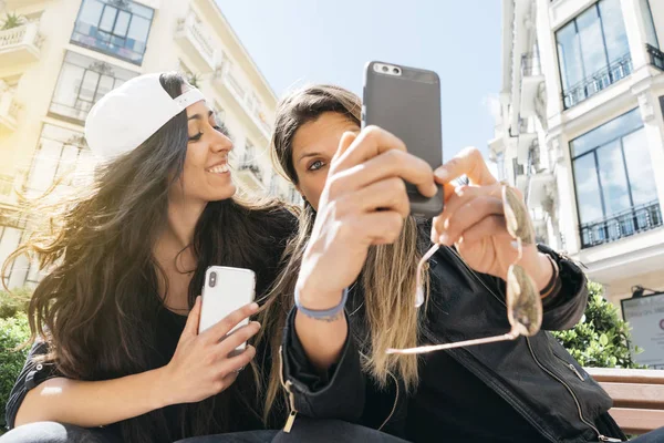 Дві жінки зі смартфоном на вулиці — стокове фото