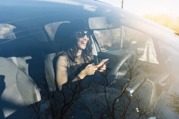 Krásná mladá žena pomocí svého mobilního telefonu v autě — Stock fotografie