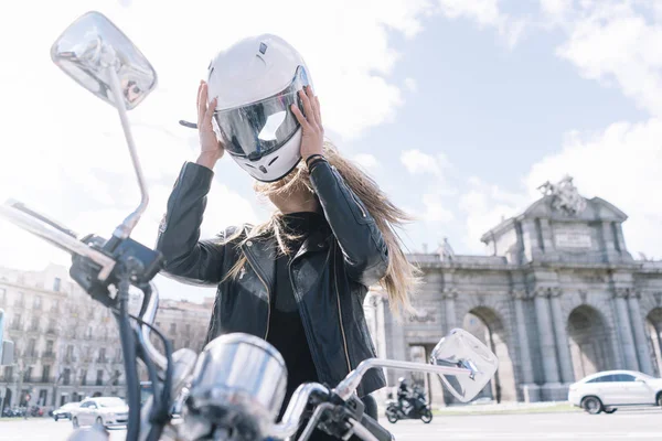 Frau mit Motorrad in der Stadt setzt es den Helm — Stockfoto