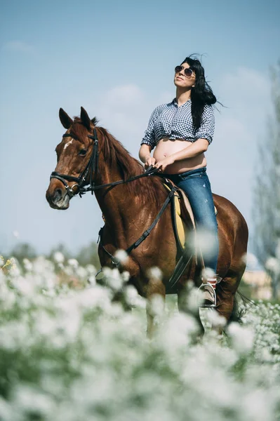 Gravid kvinna med häst i det gröna fältet — Stockfoto