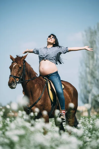 Těhotná žena s koněm v zeleném poli — Stock fotografie