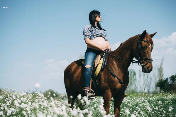 Gravid kvinna med häst i det gröna fältet — Stockfoto