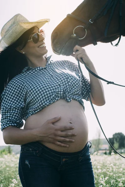 Mulher grávida com cavalo no campo verde — Fotografia de Stock