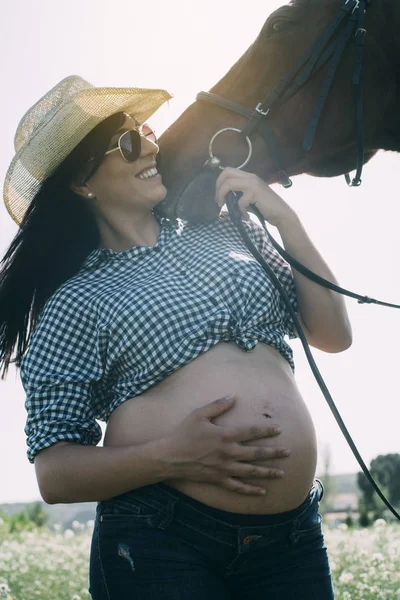 Mujer embarazada con caballo en el campo verde —  Fotos de Stock