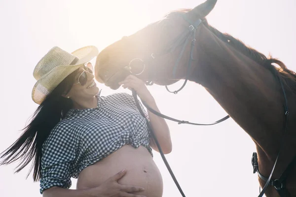 Donna incinta con cavallo nel campo verde — Foto Stock