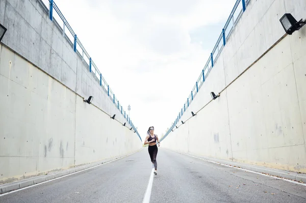 Uma bela mulher a correr na estrada. Fitness, treino, esporte, conceito de estilo de vida . — Fotografia de Stock