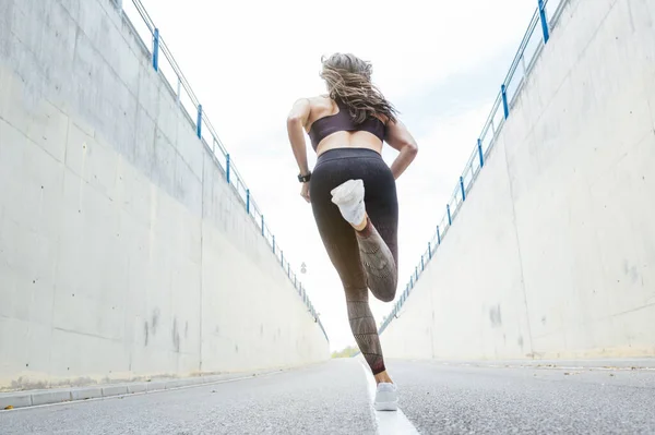 Uma bela mulher a correr na estrada. Fitness, treino, esporte, conceito de estilo de vida . — Fotografia de Stock