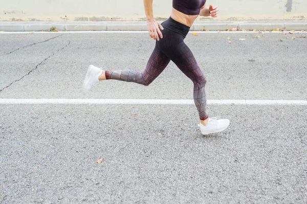 Uma mulher irreconhecível a correr na cidade. Fitness, treino, esporte, conceito de estilo de vida. — Fotografia de Stock