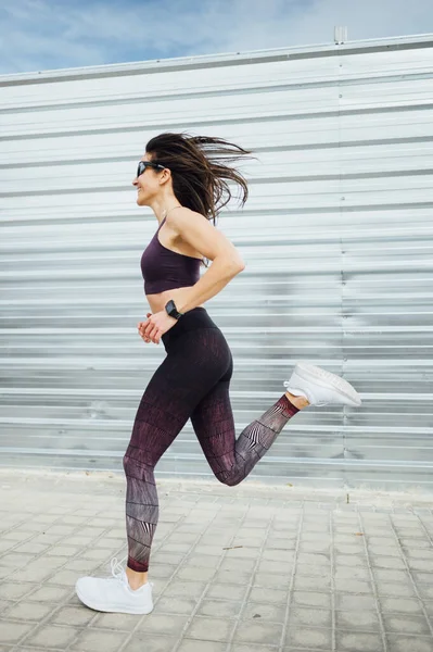 Uma bela mulher a correr na cidade. Fitness, treino, esporte, conceito de estilo de vida — Fotografia de Stock