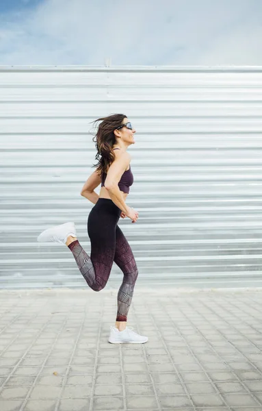 Uma bela mulher a correr na cidade. Fitness, treino, esporte, conceito de estilo de vida — Fotografia de Stock