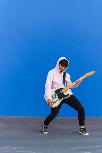 Jovem com guitarra elétrica no fundo azul — Fotografia de Stock