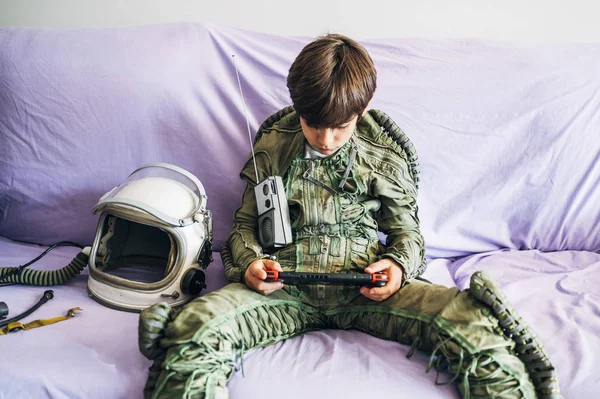 Astronot üniformalı sevimli bir çocuk. Kanepede oturuyor ve evdeki bir oyun konsoluyla oynuyor. — Stok fotoğraf