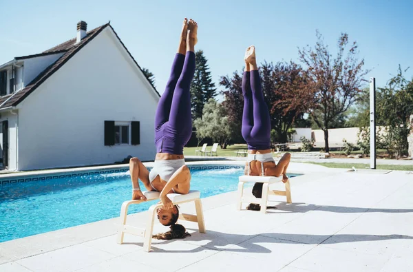 Hermanas gemelas practicando yoga junto a una piscina . — Foto de Stock