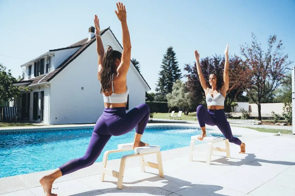 Hermanas gemelas practicando yoga junto a una piscina . — Foto de Stock