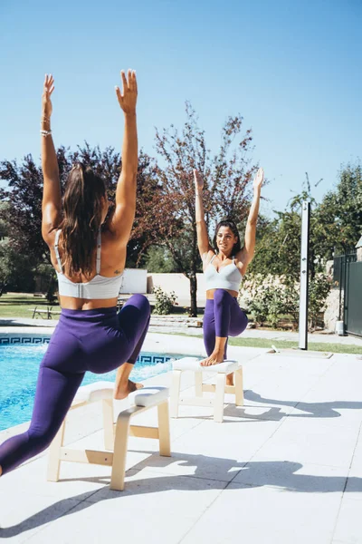 Hermanas gemelas practicando yoga junto a una piscina . — Foto de Stock
