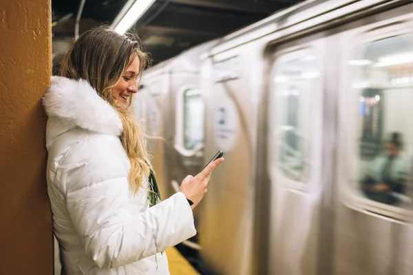 Mulher de pé perto de passagem de metrô com smartphone — Fotografia de Stock