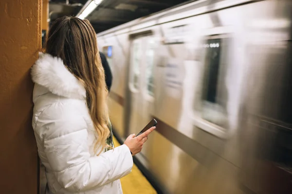 Mulher de pé perto de passagem de metrô com smartphone — Fotografia de Stock